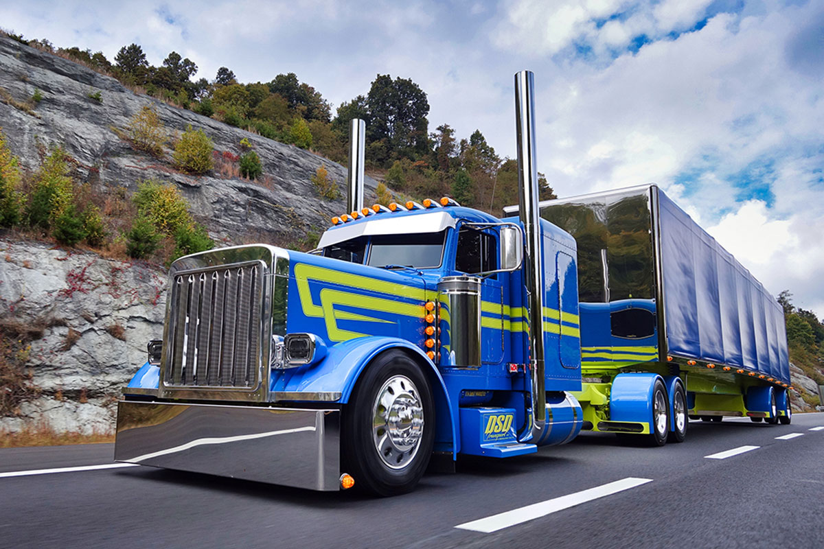 Teal Peterbilt 389 with yellow stripes on road