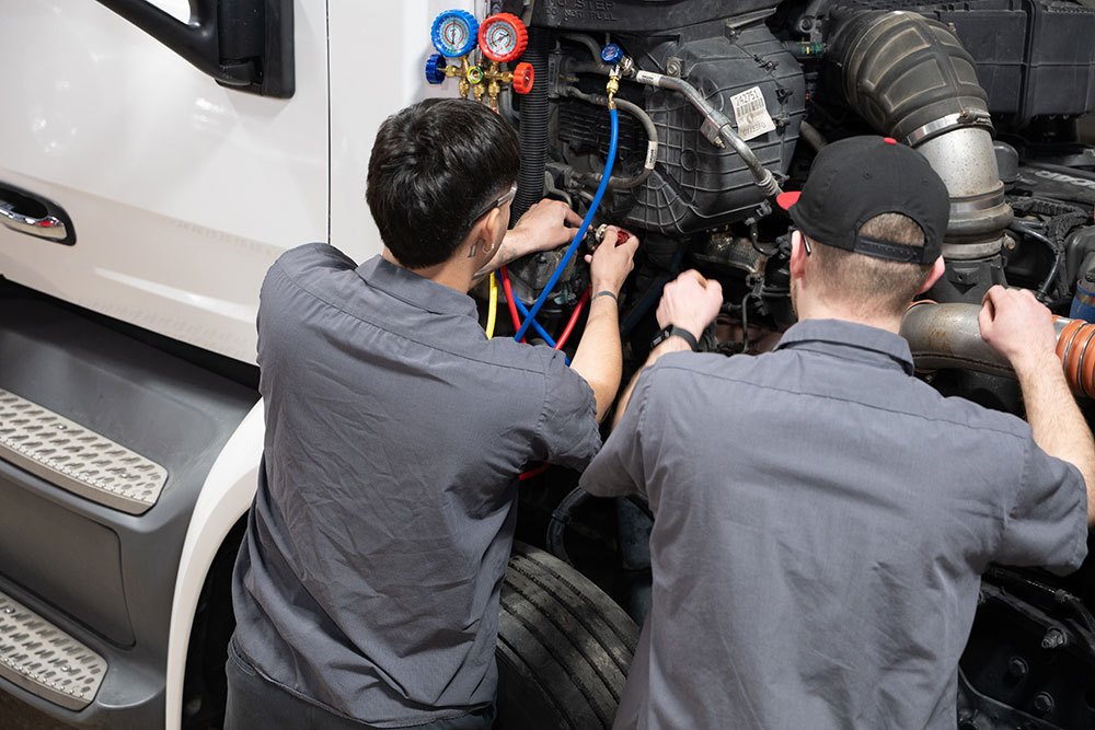 Certified heavy-duty truck technicians performing maintenance at JX Truck Center.