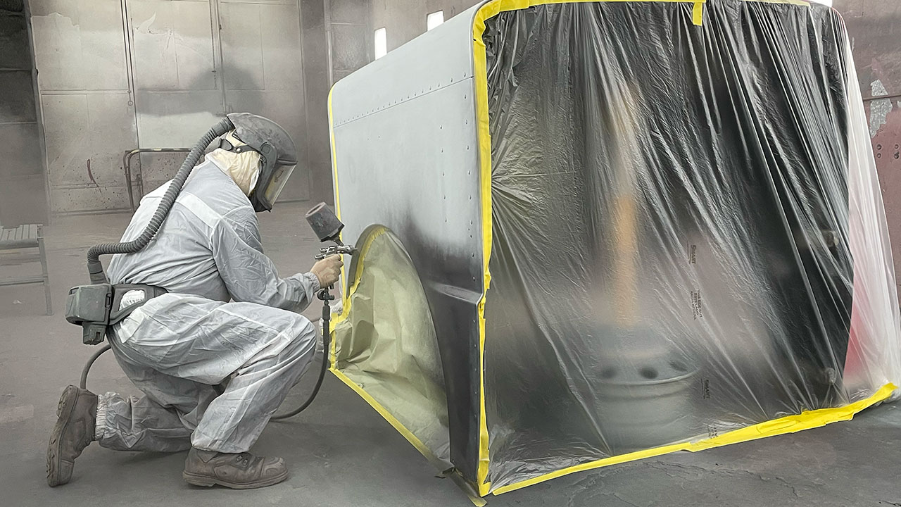 Employee painting a part at JX Truck Center's Body Shop