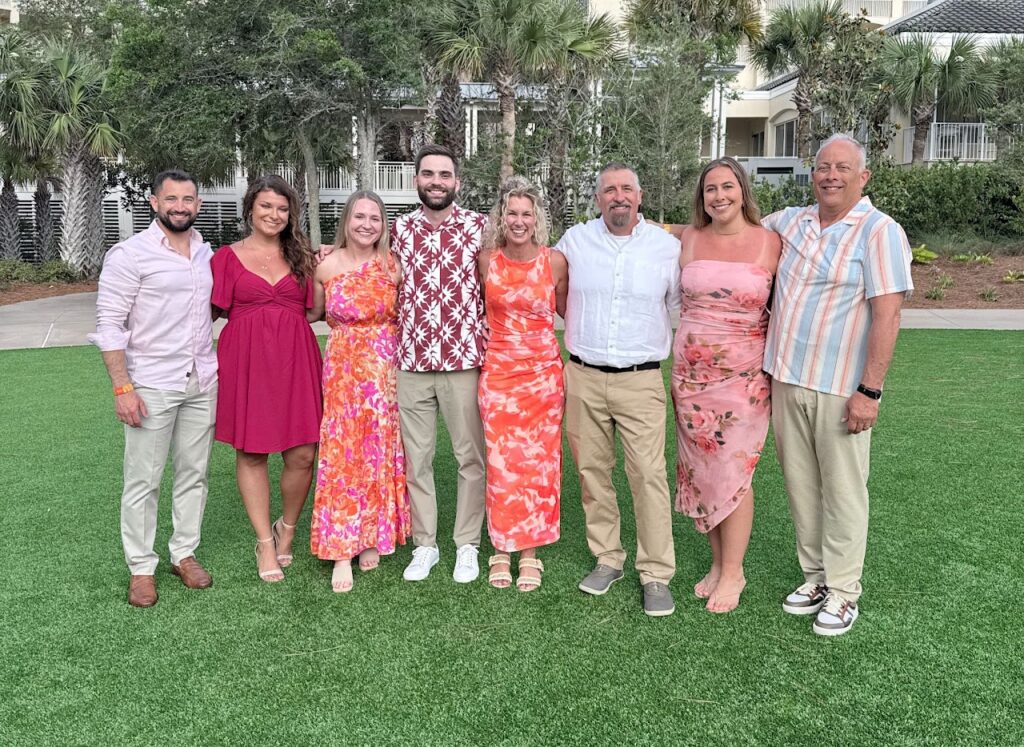 JX Truck Center team members and guests smiling together outdoors at the Peterbilt Legends Circle event on Amelia Island.